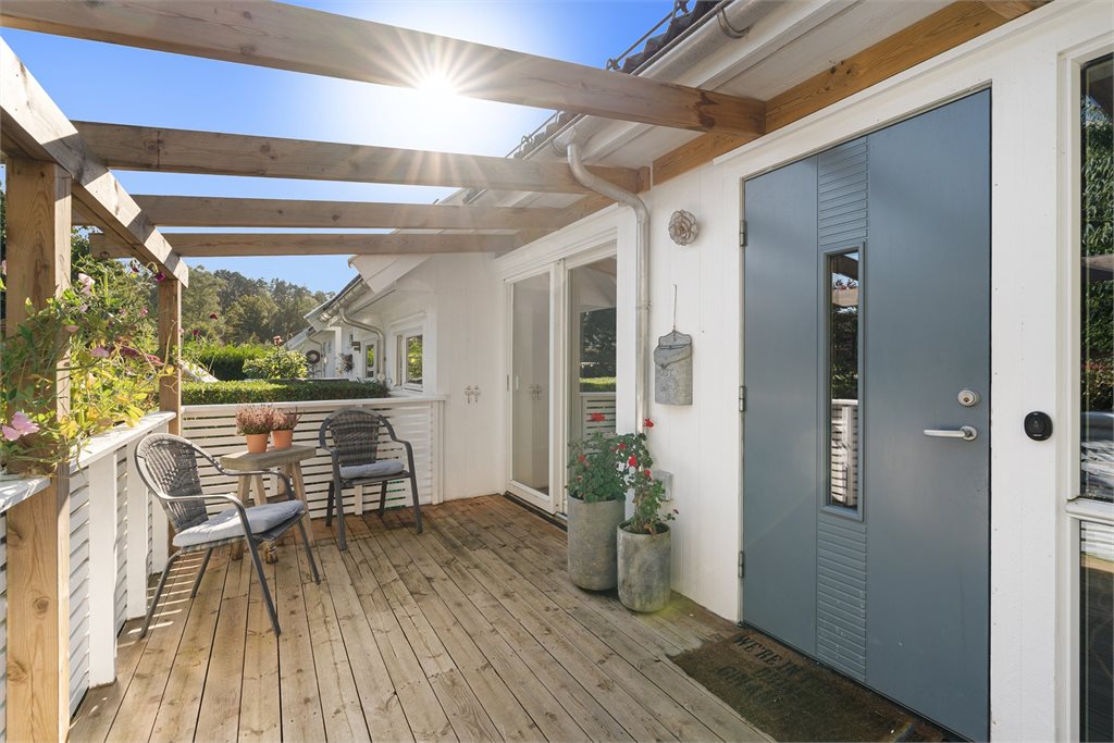 Veranda og hage ved inngangsparti og skyvedør til kjøkken. Her er det morgensol. 